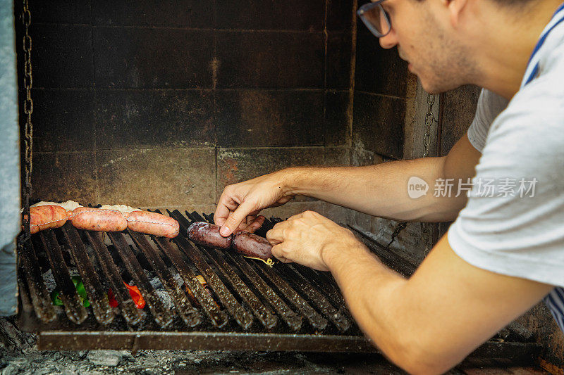 年轻男子放置肉类在阿根廷parilla Asado手工烧烤